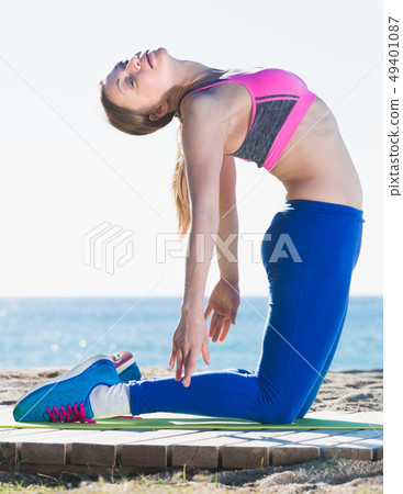 Glad woman stretching muscles on the sand 49401087