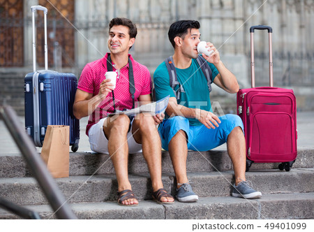 Men tourists are sitting with coffee and watching in map Men tourists are sitting with coffee and watching in map 49401099