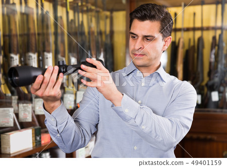 Man owner of hunting store checking optical sights 49401159