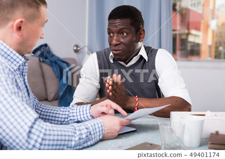 Upset man with friend looking worriedly at papers at home Upset man with friend looking worriedly at papers at home 49401174