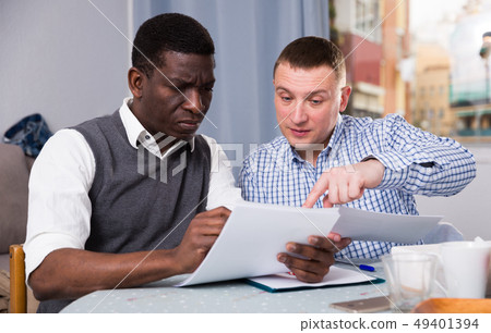 Interracial men working in home interior with documents Interracial men working in home interior with documents 49401394