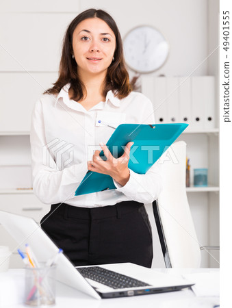 Young woman manager standing with clipboard and welcoming Young woman manager standing with clipboard and welcoming 49401555