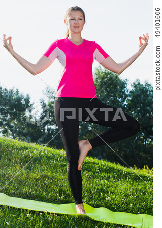 Sportswoman in pink T-shirt is staying and practising meditation 49401606