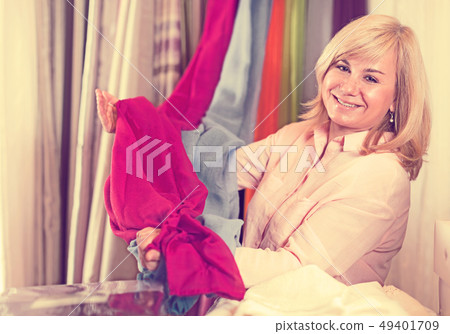 Mature woman customer choosing color curtains Mature woman customer choosing color curtains 49401709