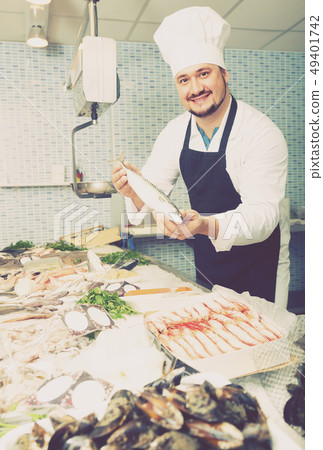 Smiling seller shows hands fish on counter Smiling seller shows hands fish on counter 49401742