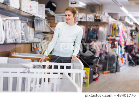 Smiling pregnant woman is choosing new crib for baby Smiling pregnant woman is choosing new crib for baby 49401770