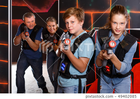 glad teen brother and sister with laser pistols playing laser tag with their parents glad teen brother and sister with laser pistols playing laser tag with their parents 49402085
