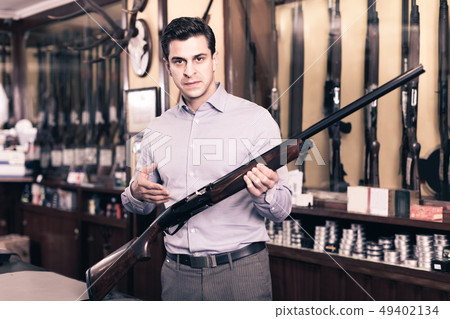 Handsome adult male in hunting shop with rifle in hands 49402134