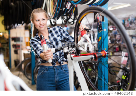 Female master is cheking wheel of modern bicycle 49402148