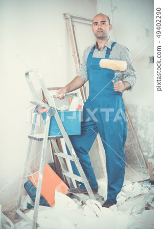 Repairer is standing with roller in uniform Repairer is standing with roller in uniform 49402290