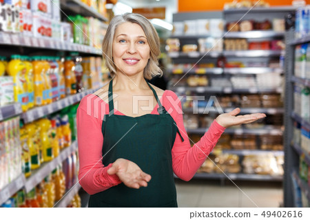 mature saleswoman inviting to grocery store