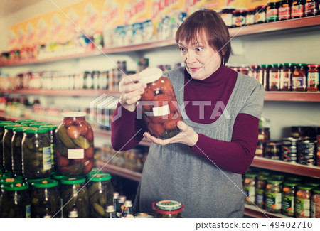 Woman consumer choosing glass jar of tomatoes 49402710