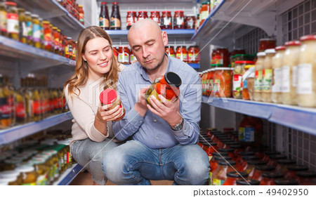 Portrait of family couple consumers choosing pickle goods Portrait of family couple consumers choosing pickle goods 49402950