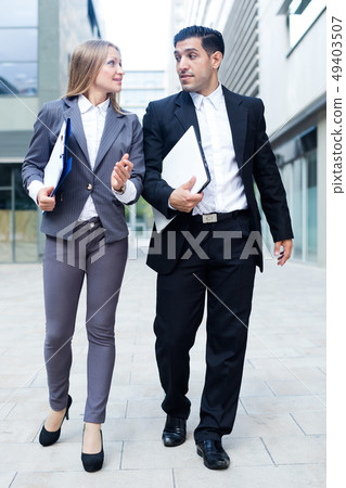 Businesswoman and her partner are going to office and talking about project 49403507