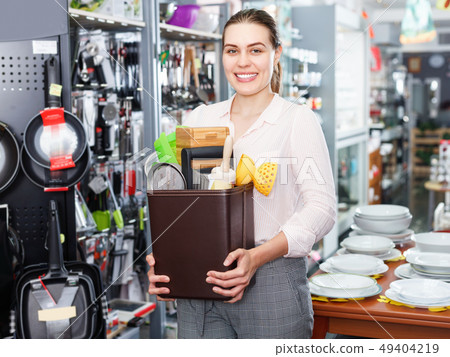 Young woman buyer holding catalogue, choosing new tableware for kitchen in store Young woman buyer holding catalogue, choosing new tableware for kitchen in store 49404219