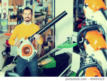 Smiling guy deciding on best leaf blower in garden equipment shop Smiling guy deciding on best leaf blower in garden equipment shop 49404323