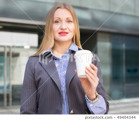 Smiling businesswoman in suit with cup of coffee Smiling businesswoman in suit with cup of coffee 49404344