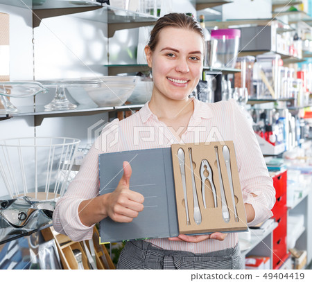 Young woman choosing cutlery sets for seafood Young woman choosing cutlery sets for seafood 49404419