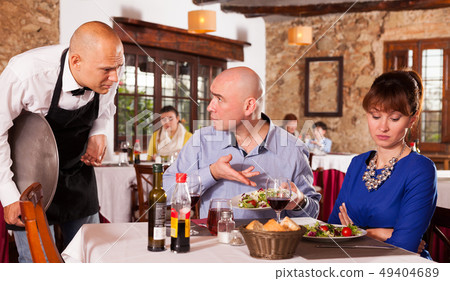 Upset couple complaining to waiter 49404689