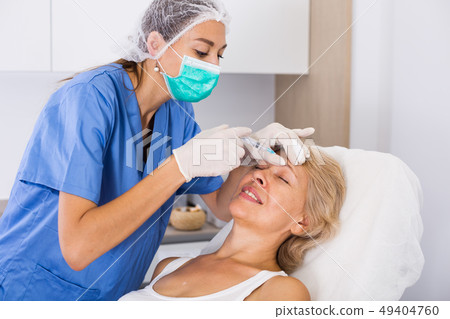 Mature female receiving cosmetic injection 49404760