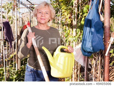 Senior woman with watering can in garden Senior woman with watering can in garden 49405006