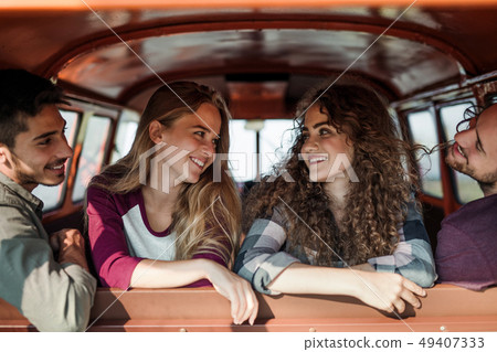 A group of young friends on a roadtrip through countryside, sitting in a car. A group of young friends on a roadtrip through countryside, sitting in a car. 49407333