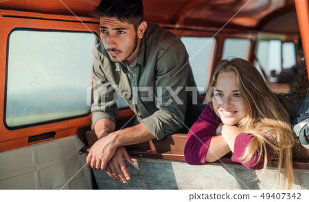A group of young friends on a roadtrip through countryside, looking out of window. 49407342