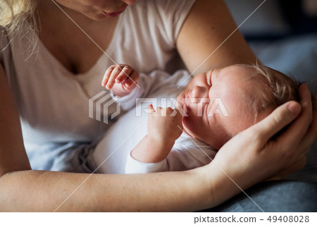 A midsection of mother with a sleeping newborn baby at home. 49408028