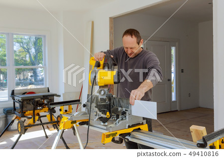 Carpenter using a circular saw to cut wood board 49410816