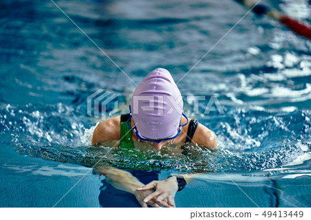 Female athlete in a green-black swimsuit  49413449