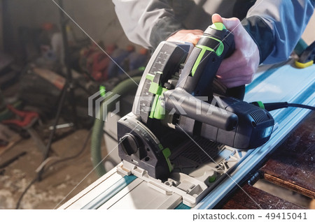 Close-up manual circular power saw in the hands of a worker in a home workshop. Starting a business 49415041