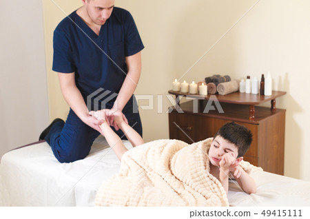 Little bored boy patient at reception at a professional masseuse. Foot Massage Therapy 49415111