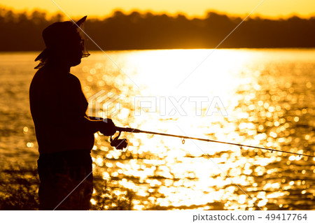 Fisherman with a fishing rod at sunset Fisherman with a fishing rod at sunset 49417764
