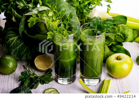 Green smoothie with fruits and vegetables on white wooden background. Green smoothie with fruits and vegetables on white wooden background. 49422214