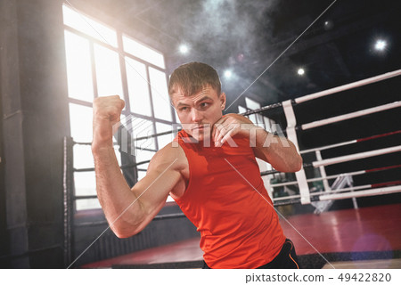 Training to become the best. Focused muscular athlete in sports clothing boxing with shadow while Training to become the best. Focused muscular athlete in sports clothing boxing with shadow while 49422820