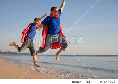 Father and son playing superhero on the beach at 49422951