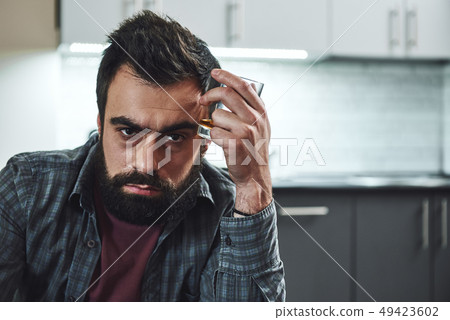Either you run the day, or the day runs you. Front view of drunk man with glass of whiskey, sitting 49423602