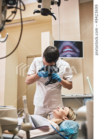 Creating brighter smiles. Dentist with camera making shots of patient's smile after treatment Creating brighter smiles. Dentist with camera making shots of patient's smile after treatment 49423699