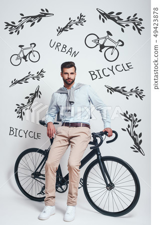 Avoiding traffic. Full length of good looking man with beard leaning on his bicycle against grey Avoiding traffic. Full length of good looking man with beard leaning on his bicycle against grey 49423878