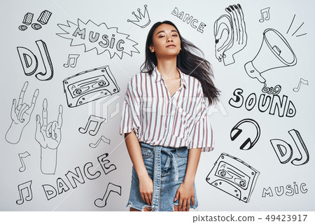 Relaxing with my favourite music...Young charming asian woman in stylish wear is looking at camera 49423917