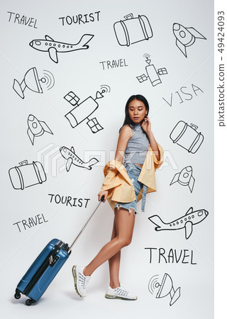 Ready for adventure! Full length of smiling beautiful asian woman carrieng her luggage while 49424093