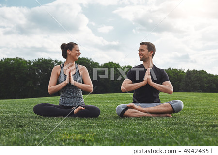 Yoga in pair. Happy couple practicing meditation exercises outdoors and looking at each other with 49424351