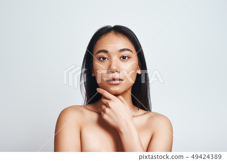 Perfect skin. Portrait of beautiful asian woman touching her skin and looking at camera while 49424389