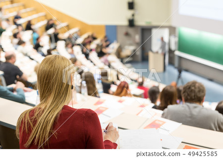 Audience in the lecture hall. Female student making notes. 49425585