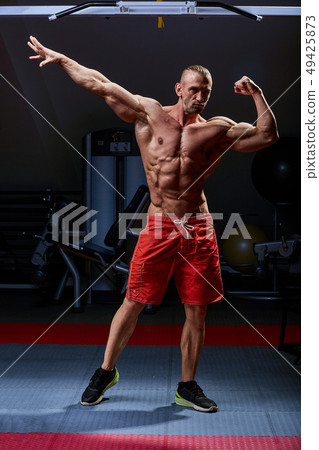 Athletic man posing. Photo of man with perfect physique on black background. Strength and motivation Athletic man posing. Photo of man with perfect physique on black background. Strength and motivation 49425873
