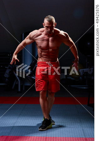 Athletic man posing. Photo of man with perfect physique on black background. Strength and motivation Athletic man posing. Photo of man with perfect physique on black background. Strength and motivation 49425876