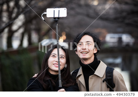 A couple taking self photos with a smartphone A couple taking self photos with a smartphone 49430379