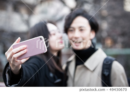 A couple taking self photos with a smartphone A couple taking self photos with a smartphone 49430670