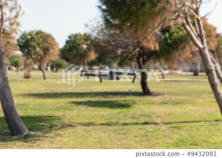 A drone with digital camera flying in the park A drone with digital camera flying in the park 49432091