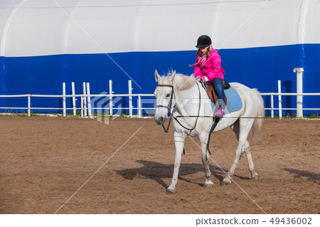 Riding lessons, little girl rides a horse 49436002